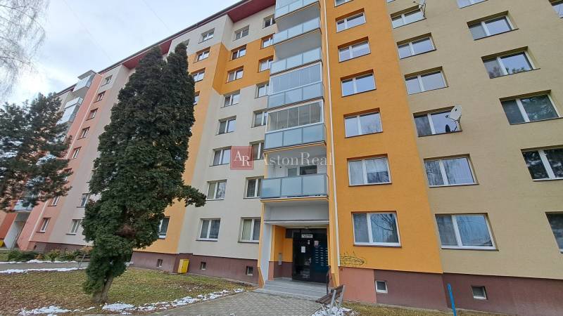 Sedmipatrový bytový dům na ulici Za dráhou v Ružomberku obklopený stromy.