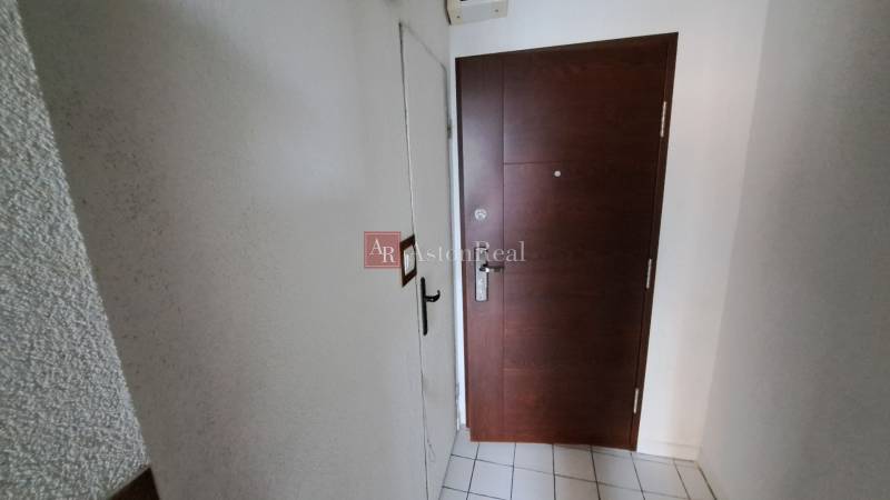 Vstupní dveře do 1-pokojového bytu s dlažbou a bílými stěnami.