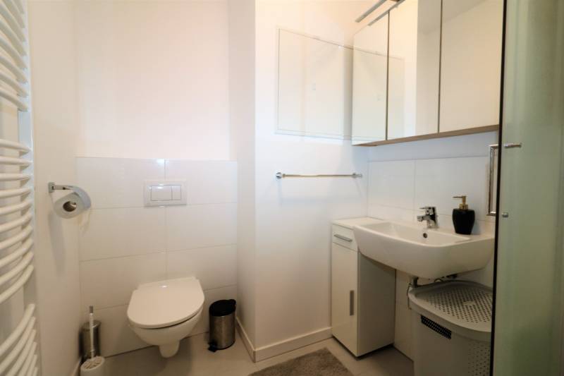 Koupelna v 2-pokojovém bytě s toaletou, umyvadlem a zrcadlovou skříňkou.