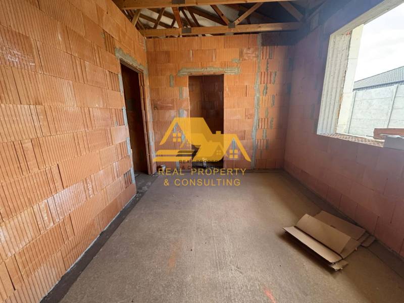 Interiér rozestavěného rodinného domu s odkrytými cihlami a stavebními materiály.