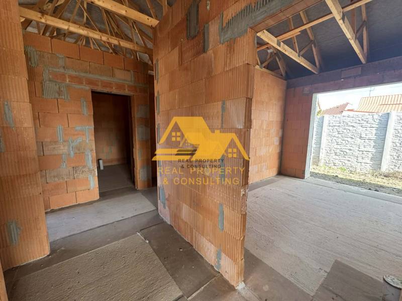 Rozestavěný rodinný dům s pohledem na stěny bez omítky a dřevěným krovem.