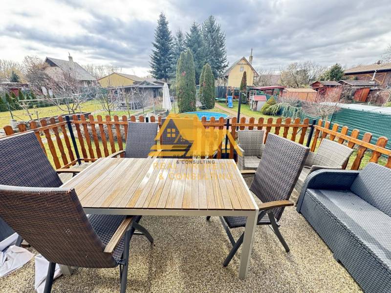 Na terase chaty v Nových Zámkoch se nachází stůl s křesly a pohovkou.