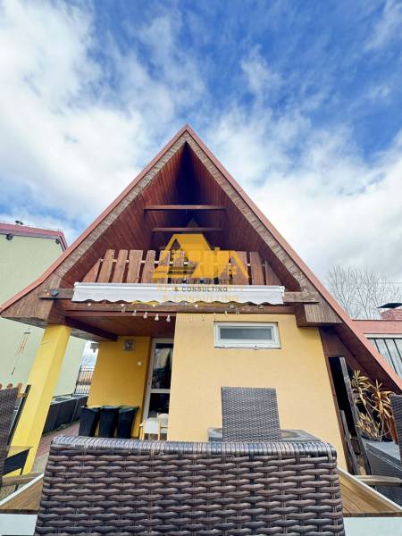 Dřevěná chata s terasou v Nových Zámcích pod modrou oblohou.