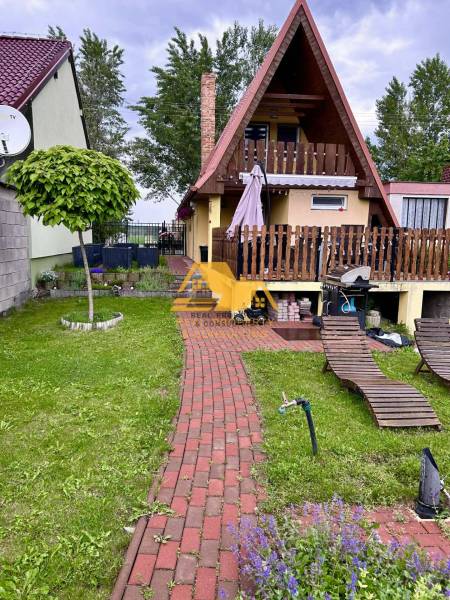 Chata v obci Nové Zámky s červenou střechou, terasou a zahradou na odpočinek.