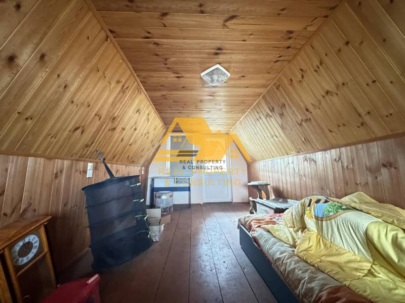 Podkroví v chatě s dřevěným dekorem a jednoduchým vybavením, příjemný prostor k odpočinku.