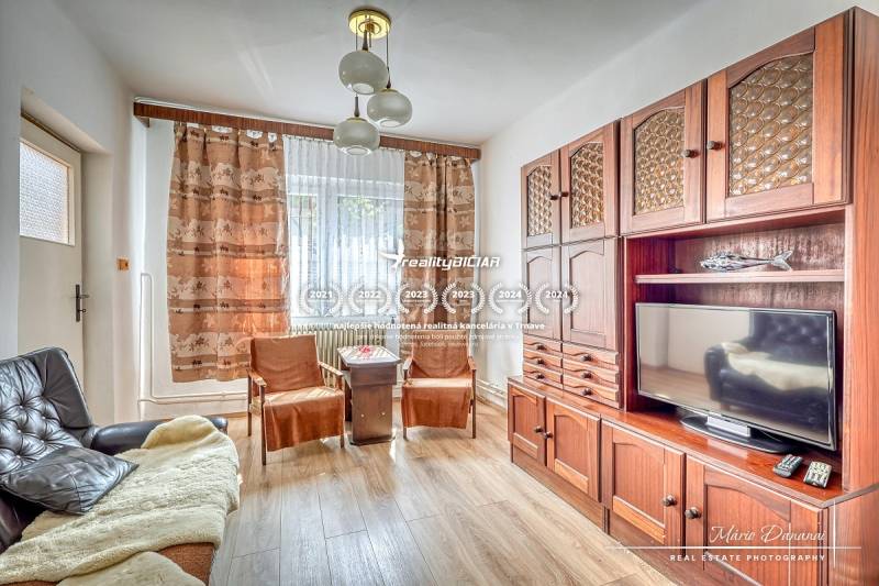 Obývací pokoj s dřevěnou sestavou, gaučem a televizí v rodinném domě.