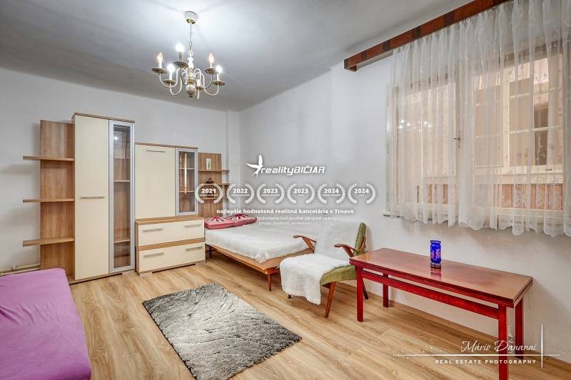 Rodinný dům s dřevěnou podlahou, lustry a nábytkem, pokoj s denním světlem.