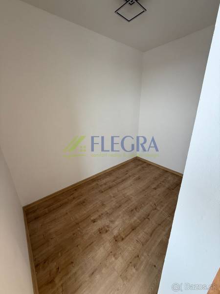 Prázdná místnost v 1-pokojovém bytě s podlahou s dřevěným dekorem, bílé stěny.