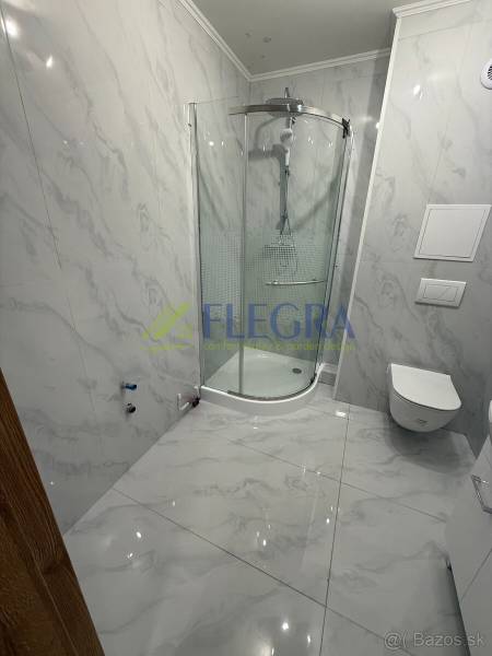 Koupelna s mramorovými obklady a sprchovým koutem v 1-pokojovém bytě.