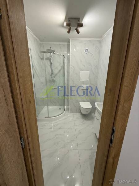 Koupelna v 1-pokojovém bytě se sprchovým koutem a keramickým obkladem.