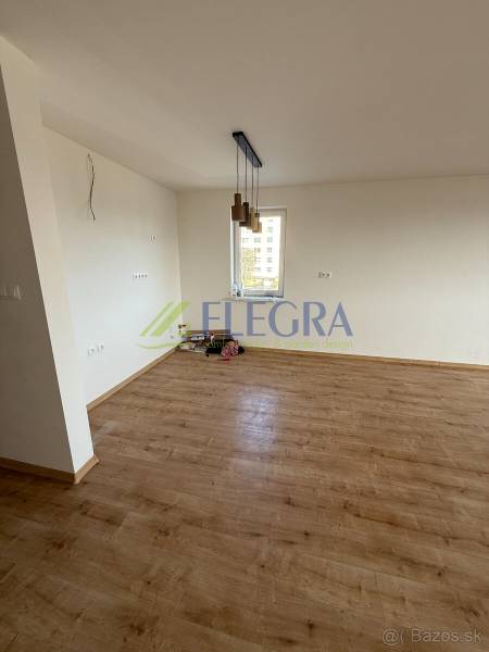 Pokoj dvoupokojového bytu s podlahou s dřevěným dekorem a závěsnými svítidly.