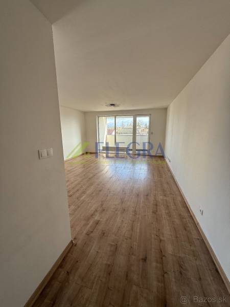 Světlý obývací pokoj s podlahou s dřevěným dekorem v 2pokojovém bytě.