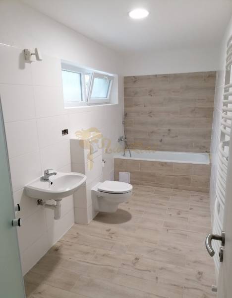 Koupelna v rodinném domě s podlahou s dřevěným dekorem, vanou a umyvadlem.