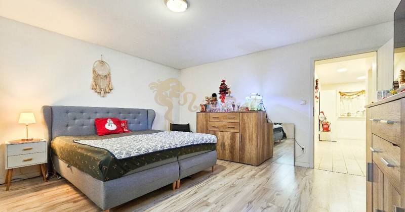 Ložnice v rodinném domě s podlahou s dřevěným dekorem a vánočními dekoracemi.