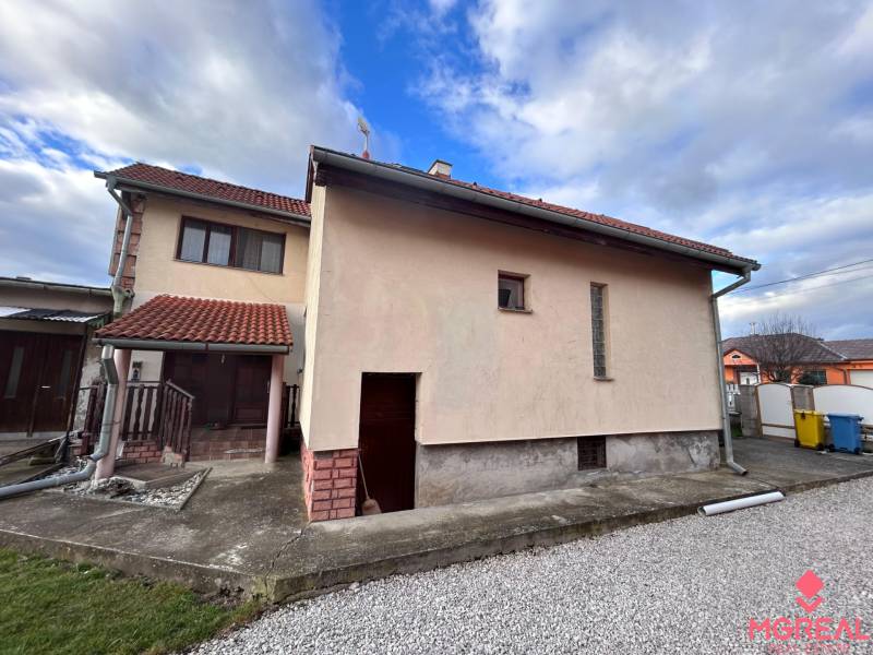 Rodinný dům v Zbehoch se šikmou střechou a chodníkem vedle garáže.