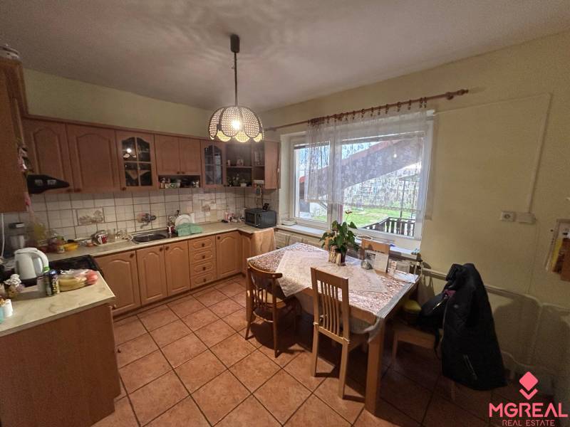 Kuchyně v rodinném domě s dřevěným dekorem a jídelním stolem.