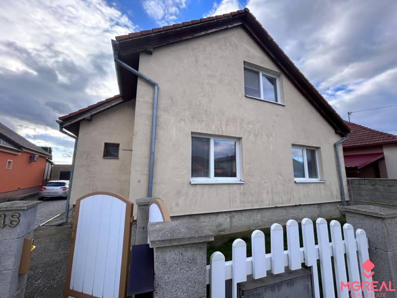 Rodinný dům v Zbehoch se šikmou střechou, plotem a příjezdovou cestou.