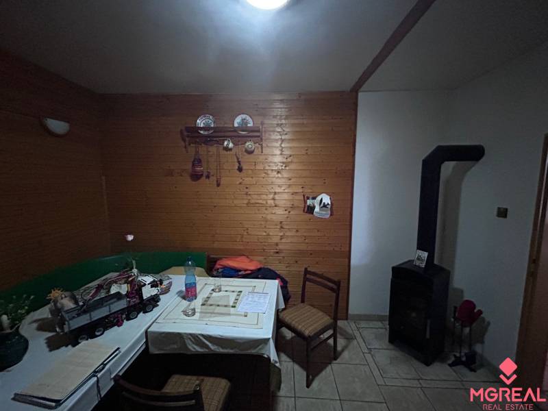 Rodinný dům s dřevěným obkladem stěn, kachlovými kamny a jídelním stolem.