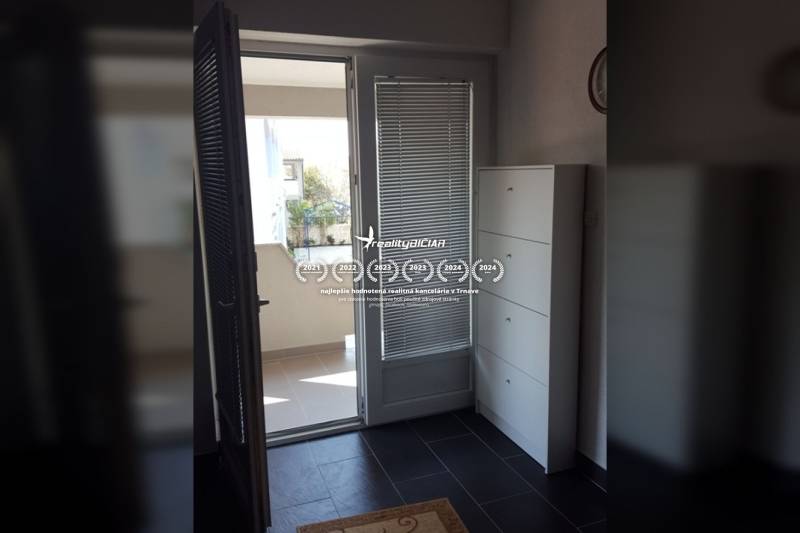 Vstup na balkon v rodinném domě s kachlovou podlahou a bílým nábytkem.