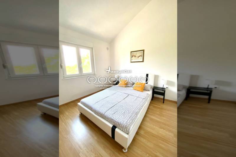 Ložnice v rodinném domě s podlahou s dřevěným dekorem, postelí a oknem.