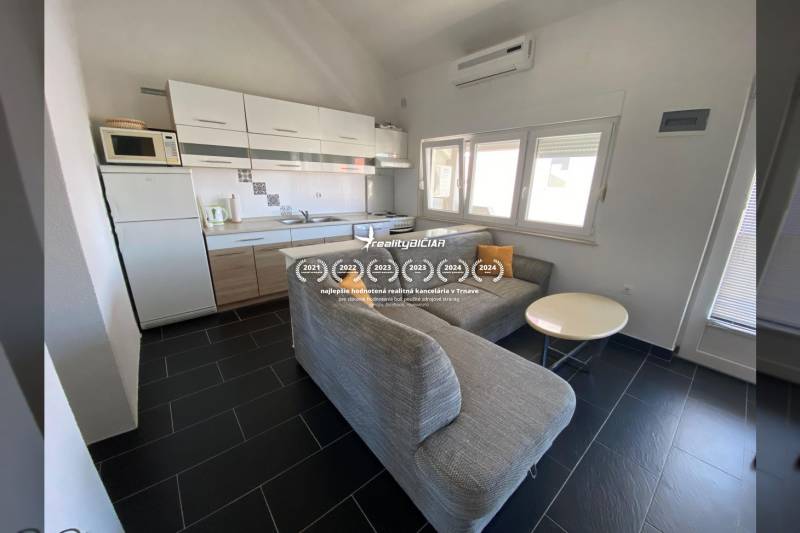 Kuchyně s rohovou pohovkou a jídelním stolem, rodinný dům, podlaha s tmavou dlažbou.