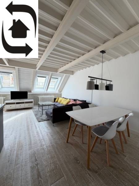 Podkrovní obývací prostor ve 4pokojovém bytě s podlahou s dřevěným dekorem a střešními okny.