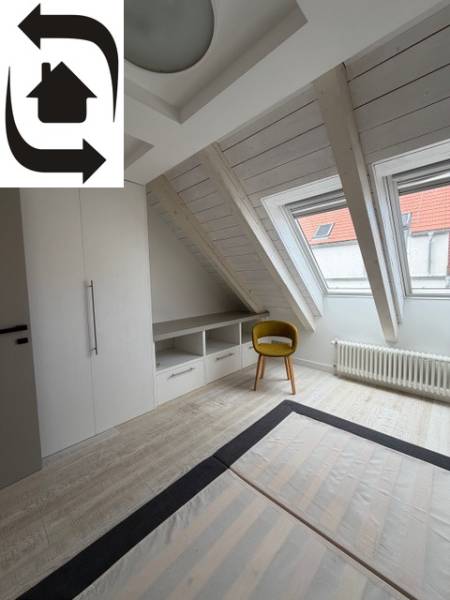 Podkrovní pokoj s podlahou s dřevěným dekorem, vestavěnou skříní a žlutou židlí.