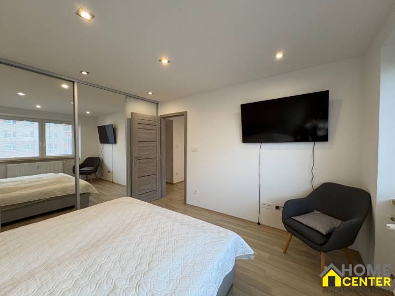 Dvoupokojový byt s TV, šatníkem a podlahou s dřevěným dekorem.