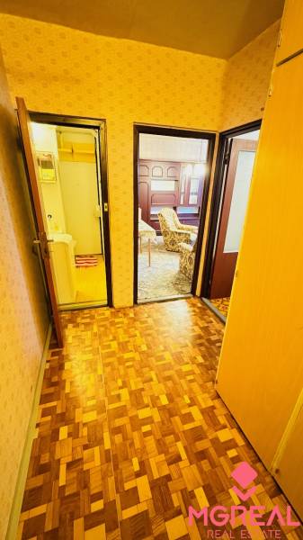 Chodba v 2-pokojovém bytě s podlahou s dřevěným dekorem a dveřmi do pokojů.