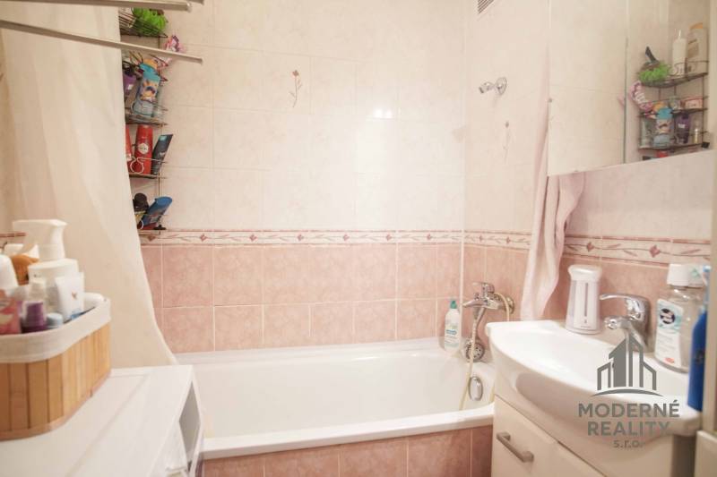 Koupelna s vanou, umyvadlem a úložným prostorem v 3-pokojovém bytě.