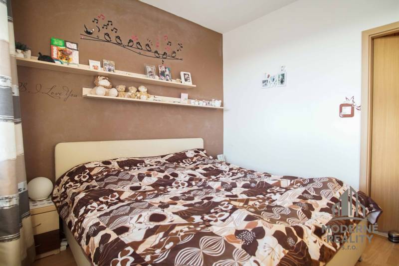 Ložnice v 3pokojovém bytě s dekorovanou stěnou a výrazným povlečením.