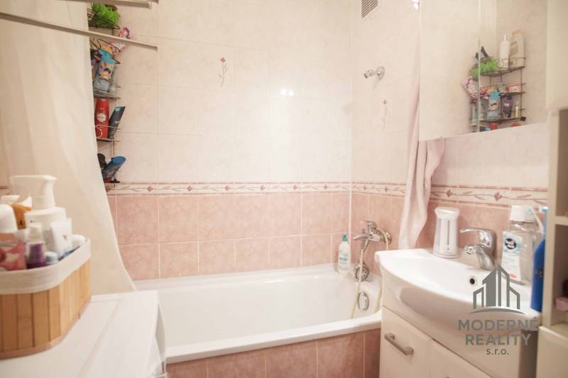 Koupelna s vanou a umyvadlem ve 3-pokojovém bytě, obklady v jemných odstínech.