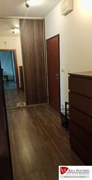 Chodba v 2-pokojovém bytě s podlahou s dřevěným dekorem, vestavěnou skříní a zrcadlovým prvkem.