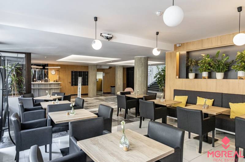 Kanceláře s podlahou s dřevěným dekorem, stoly, černými židlemi a rostlinami v Bratislavě.