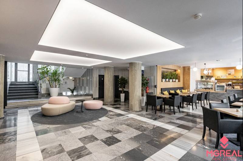 Kanceláře s černobílou podlahou, sloupy, sezením a kavárnou v interiéru.