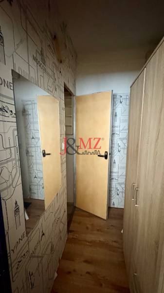 Garsonka se stěnami s cestovatelským motivem a podlahou s dřevěným dekorem.