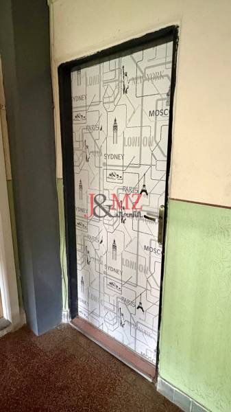 Dveře pokryté městským motivem, podlaha s dřevěným dekorem, stěna v sytě zelené barvě.