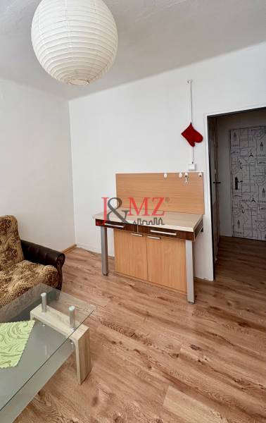 Garsonka s pohovkou, skleněným stolkem a podlahou s dřevěným dekorem.