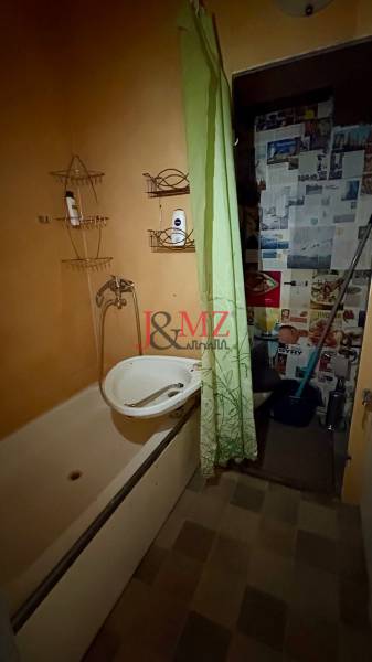 Koupelna s vanou a zeleným závěsem v garsonce.