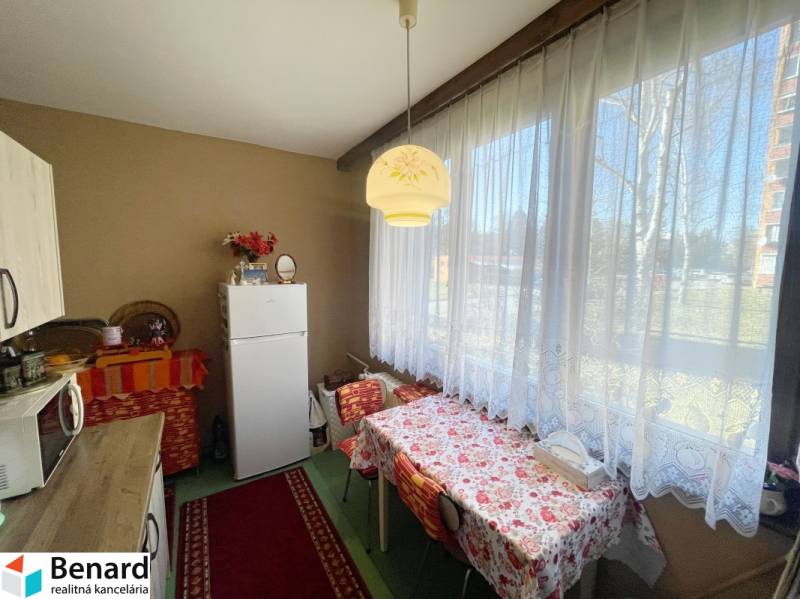 Kuchyně ve 3-pokojovém bytě s jídelním stolem a velkým oknem.