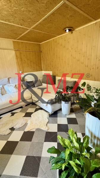 Interiér rodinného domu s rohovou sedačkou, rostlinami a vzorovanou podlahou s dřevěným dekorem.