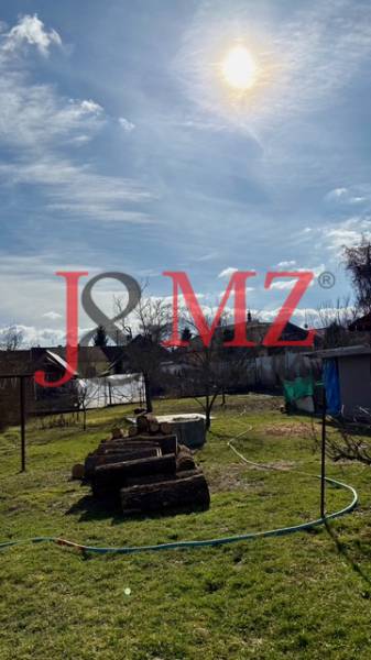 Zahrada s posekaným trávníkem a dřevem v areálu rodinného domu v Mýtných Ludanoch.