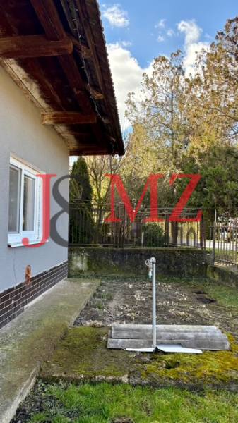 Rodinný dům v Mýtných Ludanech s boční zahrádkou a trávníkem, obklopený plotem.