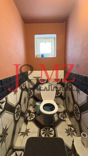 Koupelna v rodinném domě s výrazným geometrickým obkladem a oranžovými stěnami.