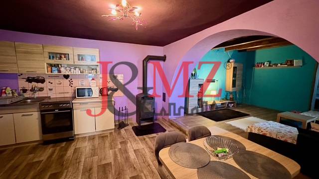 Kuchyně a obývací pokoj v rodinném domě s podlahou s dřevěným dekorem a krbem.