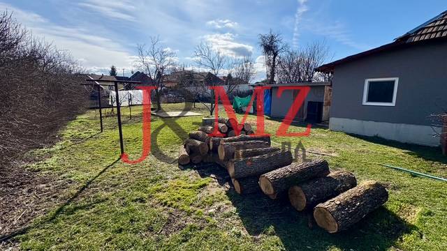 Dvůr rodinného domu v Mýtných Ludanech s hromadou dřeva a oplocením.