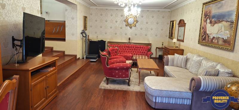 Obývací pokoj v rodinném domě s červeným nábytkem a televizorem na podlaze s dřevěným dekorem.