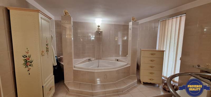 Koupelna v rodinném domě s rohovou vanou a dekorovaným nábytkem.