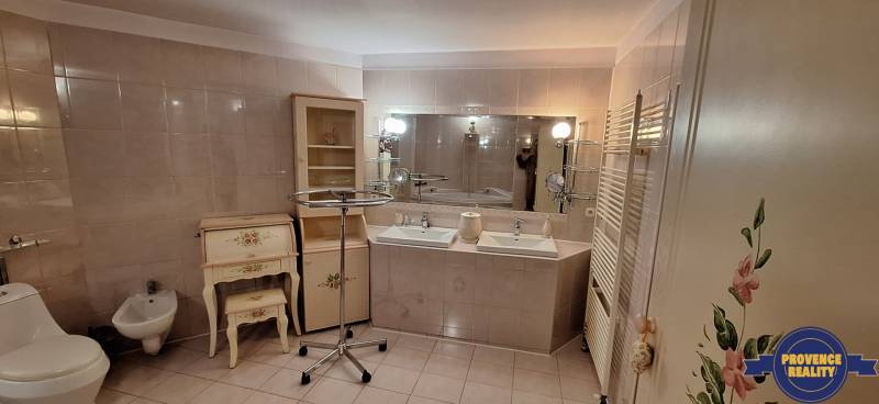 Koupelna v rodinném domě se dvěma umyvadly, zrcadlem a zdobeným nábytkem.