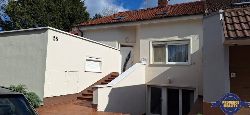 Rodinný dům v Komárně s bílou fasádou a červenou střechou.